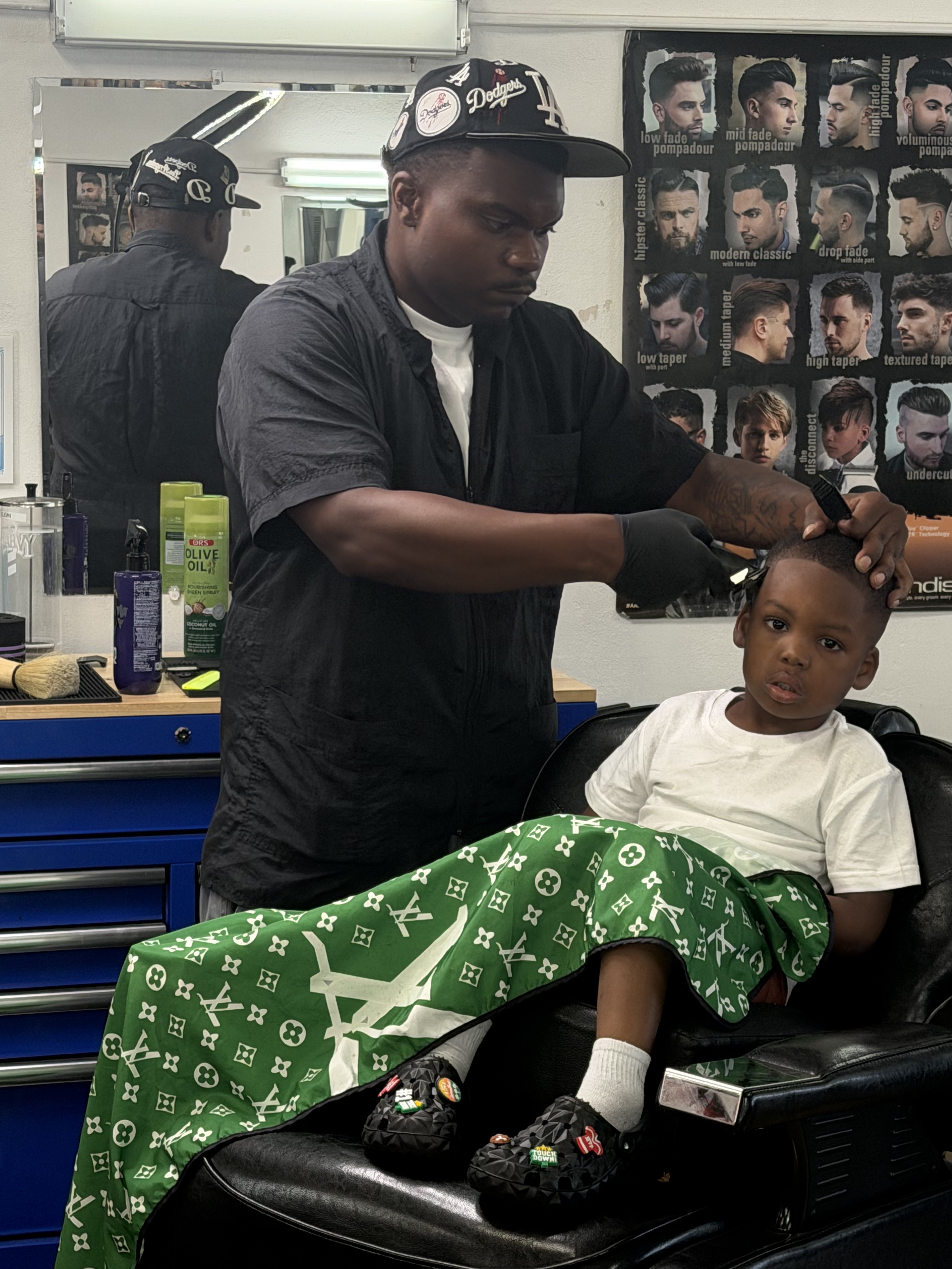 A student barber giving a young boy his first haircut at the Pasadena campus