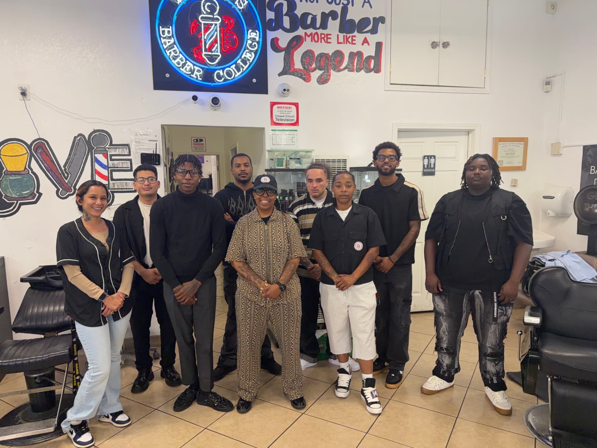 Students and staff of Borner's Barber College Pasadena gathered under the neon Barber College sign